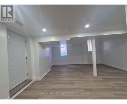 A spacious room with wooden flooring and white walls.