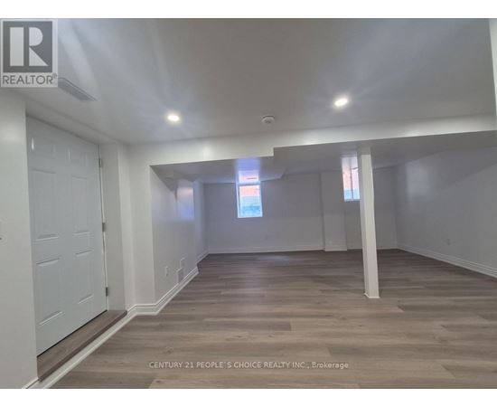 A spacious room with wooden flooring and white walls.