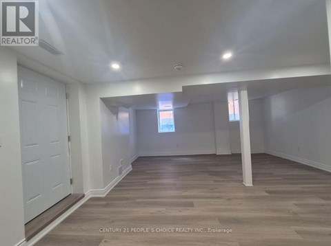 A spacious room with wooden flooring and white walls.
