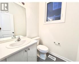 A white bathroom with a toilet, sink, and mirror.