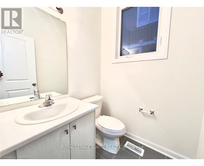 A white bathroom with a toilet, sink, and mirror.