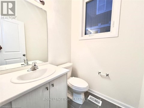 A white bathroom with a toilet, sink, and mirror.