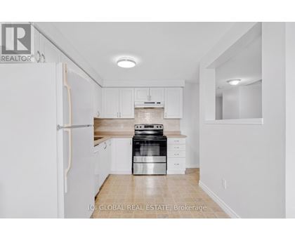 A white kitchen with a refrigerator, stove and cabinets.