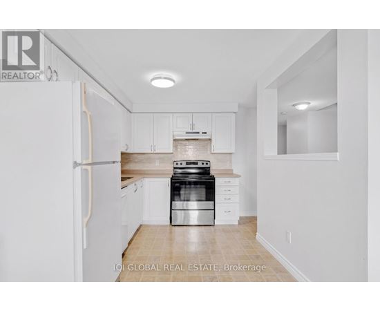 A white kitchen with a refrigerator, stove and cabinets.