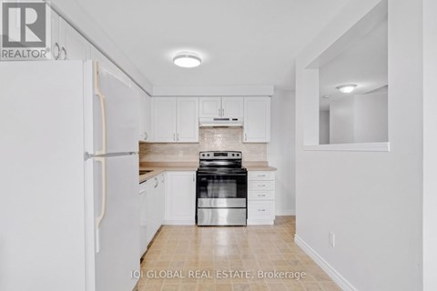 A white kitchen with a refrigerator, stove and cabinets.