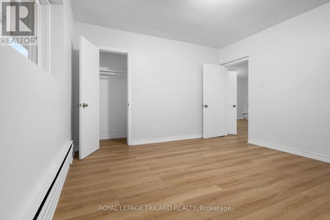 A white room with wooden floors and three doors.