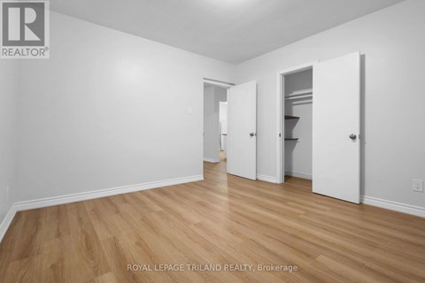 A white room with wooden floors and three white doors.