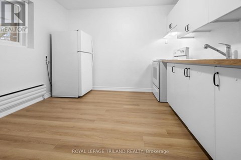 A kitchen with white cabinets and a white fridge.