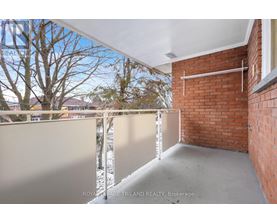 A balcony with a white railing and a brick wall.