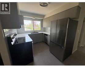 A kitchen with a refrigerator, sink, and cabinets.