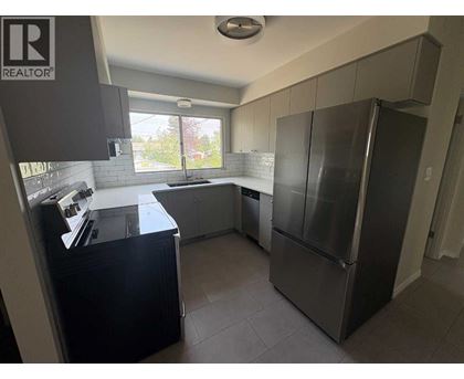A kitchen with a refrigerator, sink, and cabinets.