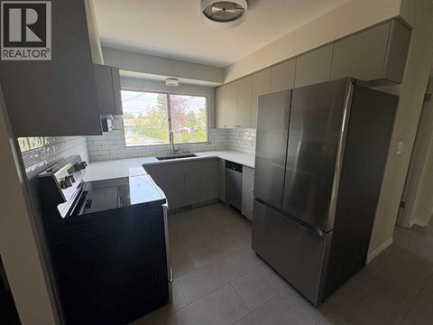 A kitchen with a refrigerator, sink, and cabinets.