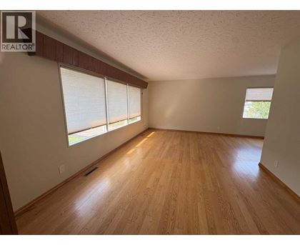 A room with wooden floors and a window with blinds.