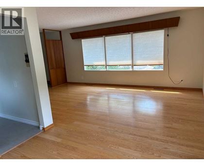 A room with wooden floors and a window with blinds.