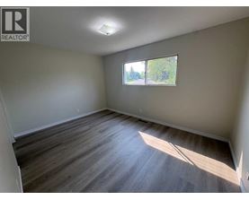 A room with wooden flooring and a window letting in sunlight.