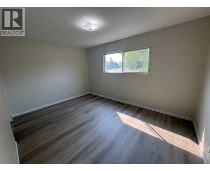 A room with wooden flooring and a window letting in sunlight.