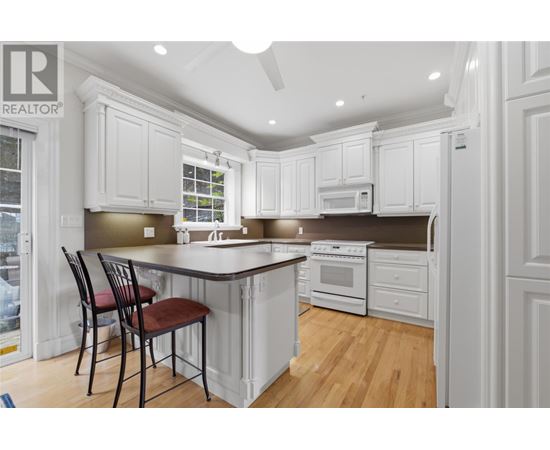 A kitchen with white cabinets and a wooden floor.