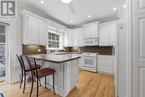 A kitchen with white cabinets and a wooden floor.