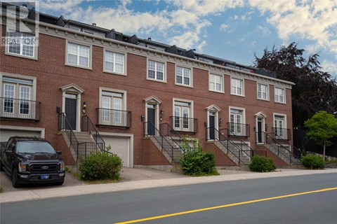 A black truck is parked on the side of a street in front of a red brick building.