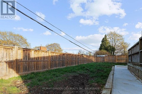 A fenced yard with a sidewalk and a grassy area.