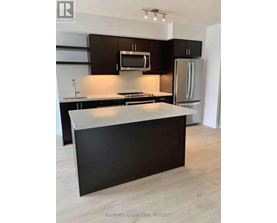 A kitchen with a black counter top and a white fridge.