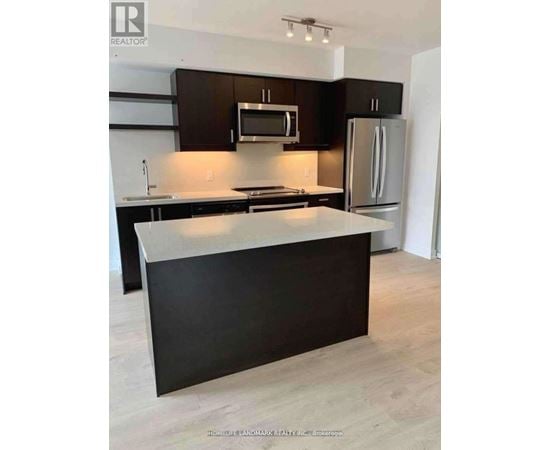 A kitchen with a black counter top and a white fridge.