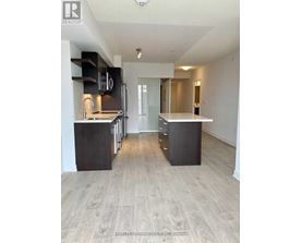 A spacious kitchen with a refrigerator, oven, and sink.