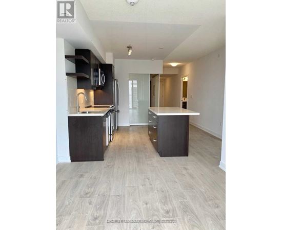 A spacious kitchen with a refrigerator, oven, and sink.