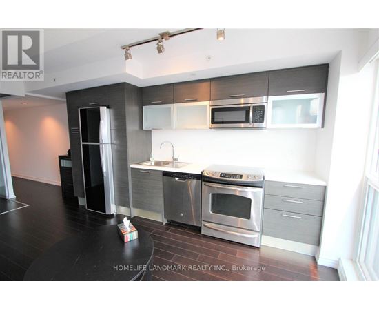 A modern kitchen with stainless steel appliances and a black countertop.