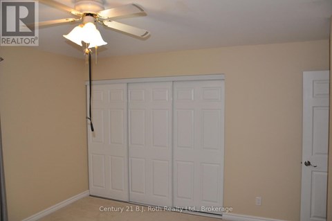A room with a ceiling fan and a white door.