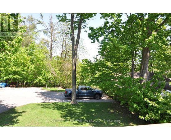 A blue truck is parked in a driveway surrounded by green trees.