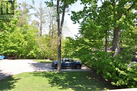 A blue truck is parked in a driveway surrounded by green trees.