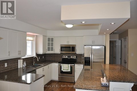 A kitchen with white cabinets and a black countertop.