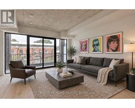 A living room with a grey couch, a coffee table, and a large window with a view of a building.