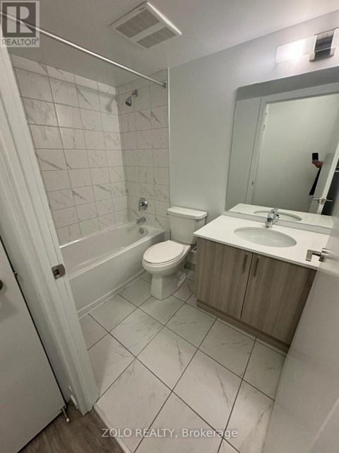 A bathroom with a toilet, sink, and mirror.