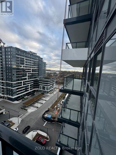 A modern glass building with a parking lot in front.