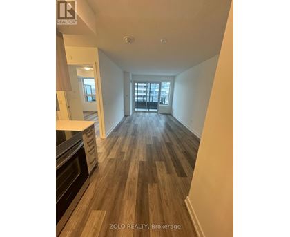 A spacious room with wooden flooring and a large window.