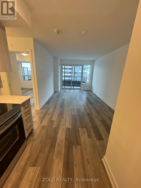 A spacious room with wooden flooring and a large window.