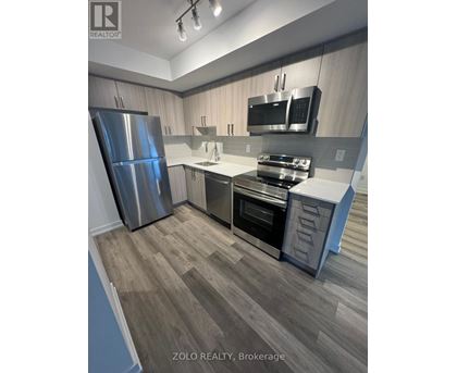 A kitchen with a refrigerator, oven, and microwave.