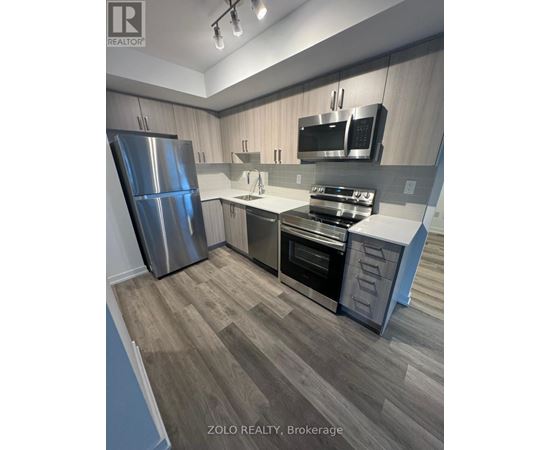 A kitchen with a refrigerator, oven, and microwave.