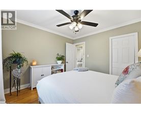A bedroom with a white bed and a ceiling fan.