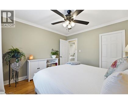A bedroom with a white bed and a ceiling fan.