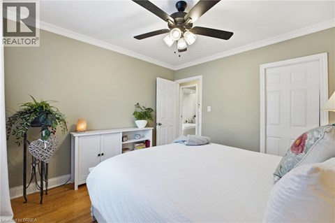 A bedroom with a white bed and a ceiling fan.