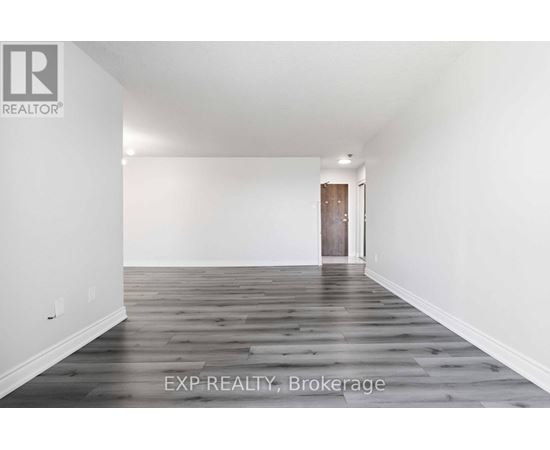 A room with wooden flooring and a door in the background.