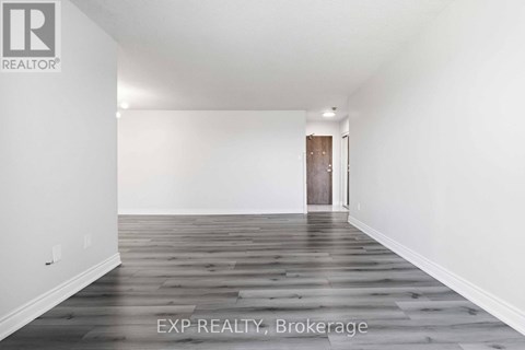 A room with wooden flooring and a door in the background.