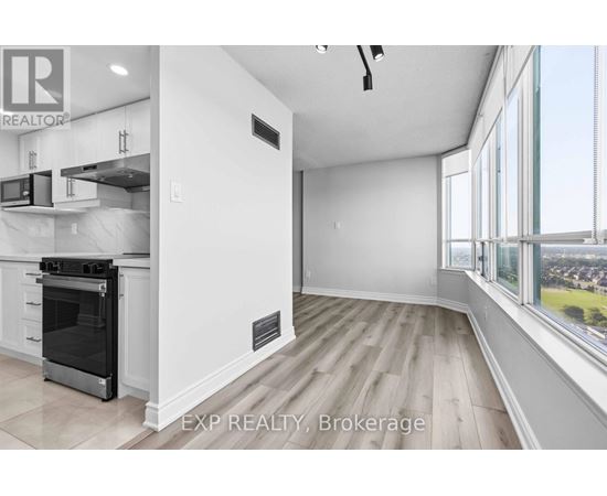 A modern kitchen with white cabinets and a large window overlooking a cityscape.