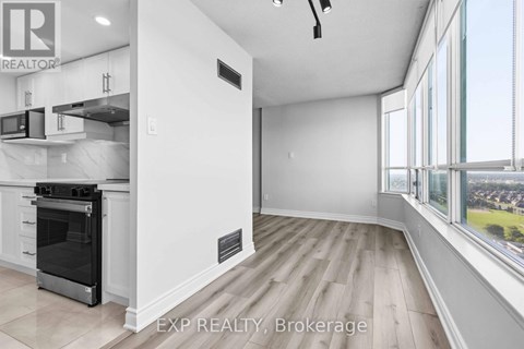 A modern kitchen with white cabinets and a large window overlooking a cityscape.