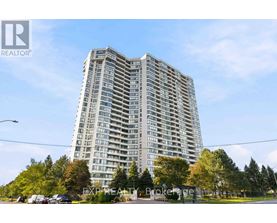 A tall residential building with a parking lot in front.