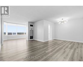 A large, empty room with wooden flooring and white walls.