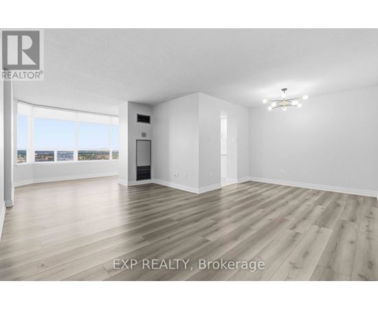 A large, empty room with wooden flooring and white walls.